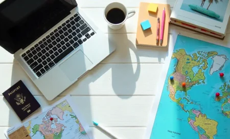 Travel itinerary planning essentials: laptop, map, passport, phone with apps on desk - organized trip planning setup